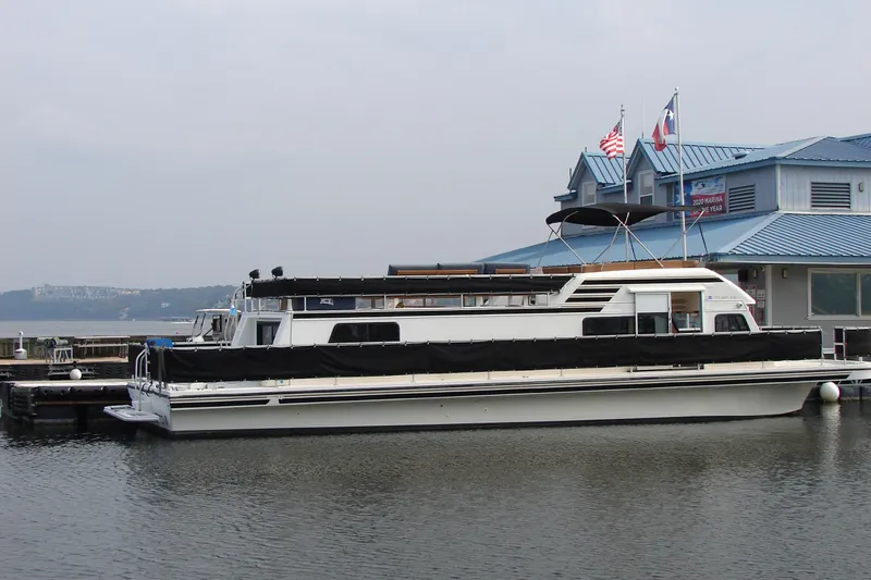 Slide: The Image of 1997 Gibson 47 Sport Houseboat docked near marina with flags. - 50