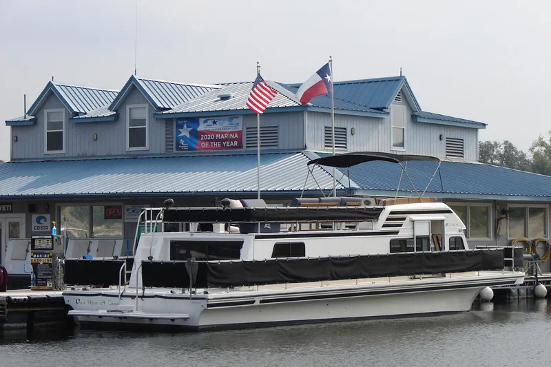 Slide: The Image of 1997 Gibson 47 Sport Houseboat docked at award-winning marina with flags. - 52