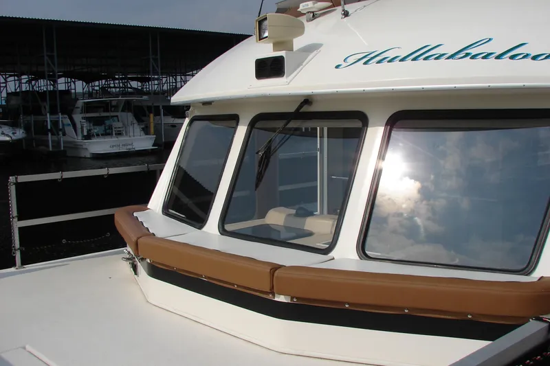 Slide: The Image of 1997 Gibson 47 Sport Houseboat docked, featuring large windows and cushioned seating. - 53