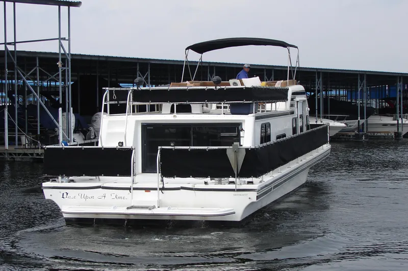 Slide: The Image of 1997 Gibson 47 Sport Houseboat docked at marina, rear view with canopy and railings. - 9