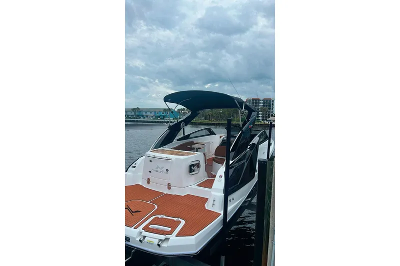 Slide: The Image of 2024 NX Boats NX260 docked, featuring sleek design and spacious deck under cloudy skies. - 3