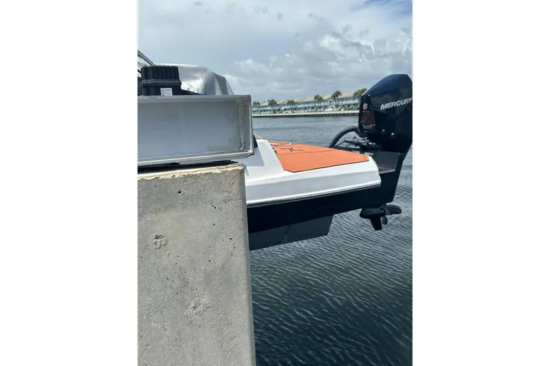 Slide: The Image of 2024 NX Boats NX260 docked with Mercury outboard motor, calm waters in background. - 5