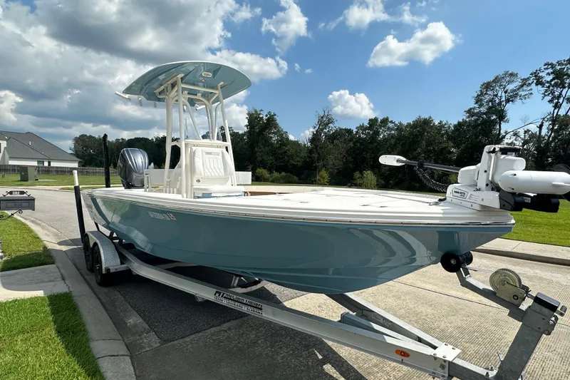 The Image of 2021 Pathfinder 2500 Hybrid boat on trailer, parked outdoors under a partly cloudy sky. - 1