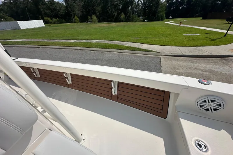 Slide: The Image of 2021 Pathfinder 2500 Hybrid boat interior with wood accents and speaker, parked near grassy area. - 22