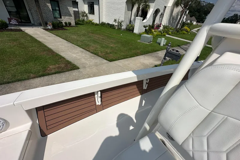 Slide: The Image of 2021 Pathfinder 2500 Hybrid boat interior with white seating, docked near a house. - 23