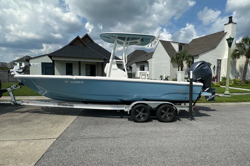 Slide: The Image of 2021 Pathfinder 2500 Hybrid boat on trailer, parked in residential area under cloudy sky. - 4