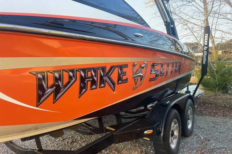 Slide: The Image of 2011 Malibu Wakesetter 21 VLX boat with vibrant orange design on trailer. - 6