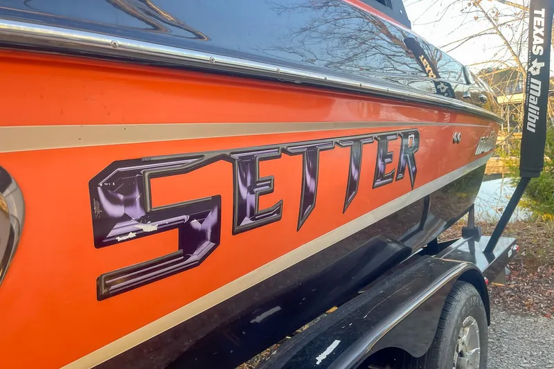 Slide: The Image of 2011 Malibu Wakesetter 21 VLX boat with orange and black design on trailer. - 7