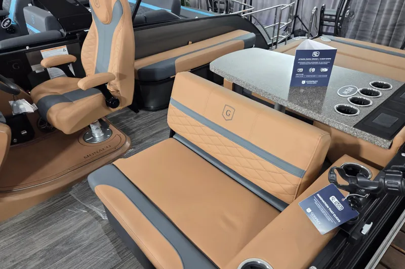 Slide: The Image of 2026 Godfrey Monaco 255 MTF boat interior with tan and gray seating, cup holders, and table. - 3