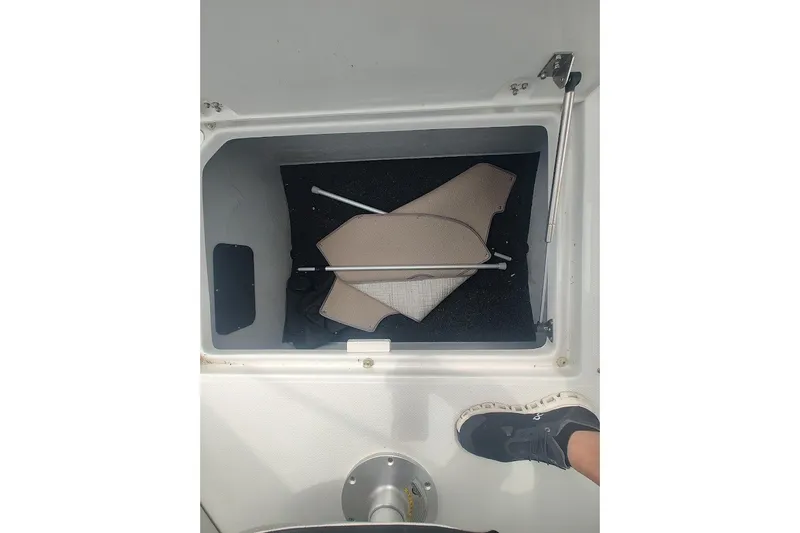 Slide: The Image of Storage compartment in 2022 Crownline 280 SS boat, featuring carpet and support pole. - 18