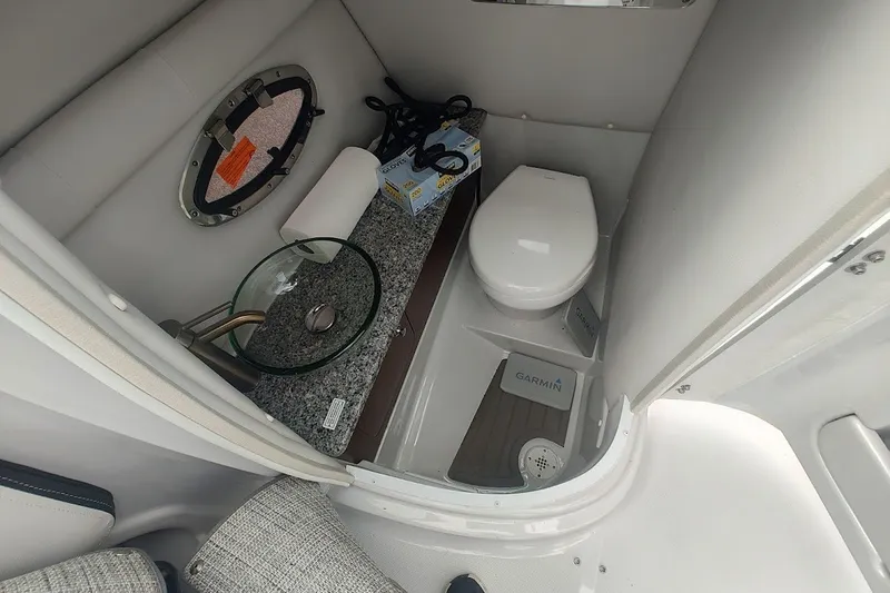 Slide: The Image of 2022 Crownline 280 SS boat bathroom with modern sink, toilet, and porthole window. - 14
