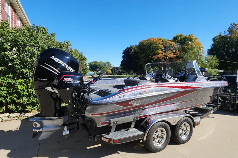 Slide: The Image of 2017 Triton 216 Fishunter boat with Mercury engine, parked outdoors on a sunny day. - 2