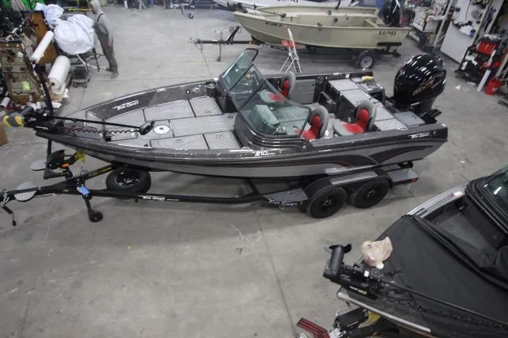 Slide: The Image of 2026 Yar-Craft 210 TFX fishing boat in a workshop, featuring dual consoles and red seating. - 1