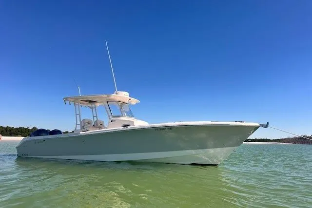 The Image of 2015 Edgewater 320CC boat anchored in clear water under a bright blue sky. - 0
