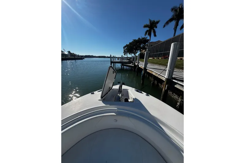 Slide: The Image of Bow view of 2015 Edgewater 320CC boat docked by palm trees. - 11
