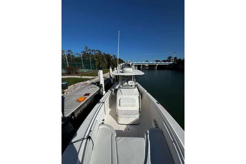 Slide: The Image of 2015 Edgewater 320CC boat docked by a calm waterfront under clear blue skies. - 12
