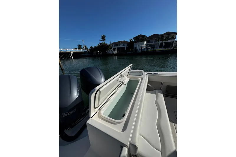 Slide: The Image of 2015 Edgewater 320CC boat with open storage compartment, docked near waterfront homes. - 17