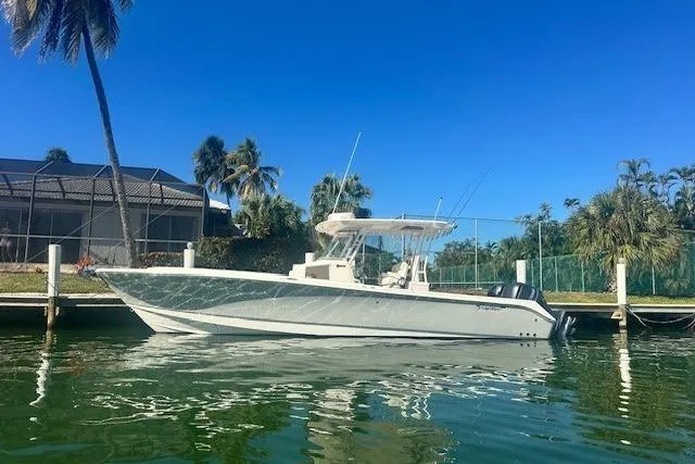 Slide: The Image of 2015 Edgewater 320CC boat docked by tropical waterfront homes. - 2