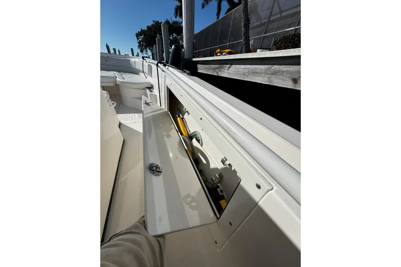 Slide: The Image of 2015 Edgewater 320CC boat with open storage compartment, docked under clear blue sky. - 26