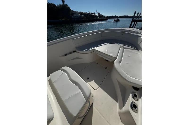 Slide: The Image of 2015 Edgewater 320CC boat interior with cushioned seating, docked by calm waters. - 27