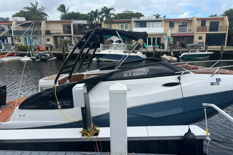 The Image of 2024 NX Boats NX270 docked in a marina, surrounded by waterfront homes and other boats. - 1