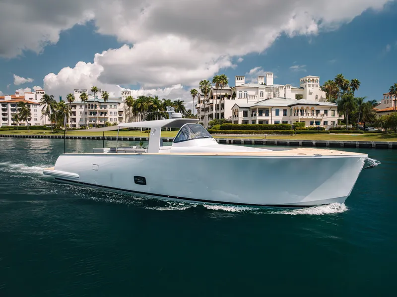 The Image of 2021 Alen 55 yacht cruising near luxury waterfront homes under a cloudy sky. - 0
