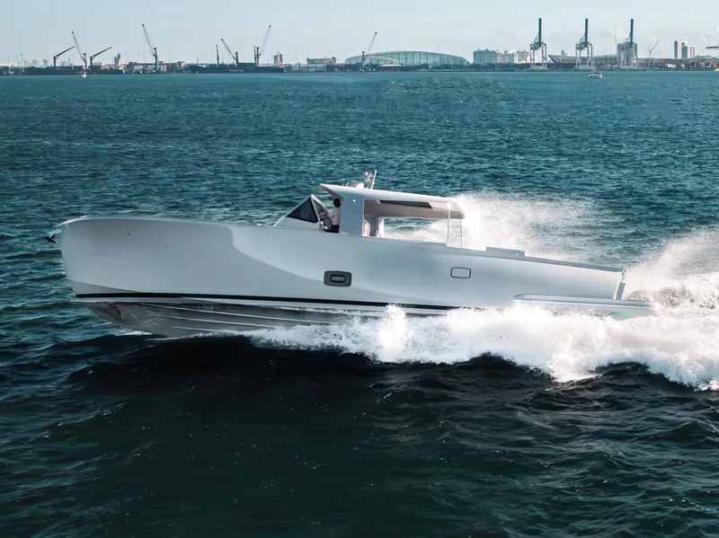 Slide: The Image of 2021 Alen 55 yacht cruising on open water with city skyline in background. - 24