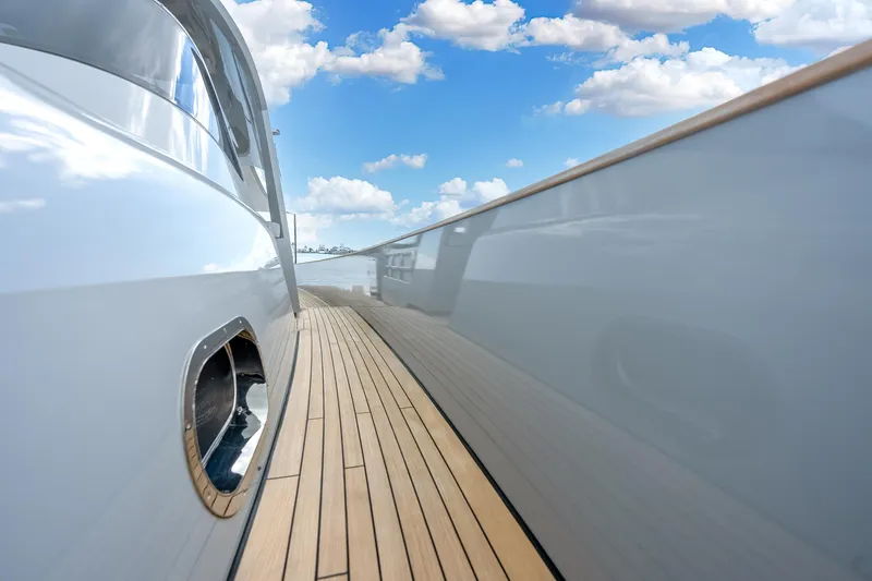Slide: The Image of Sleek Alen 55 yacht deck, 2021 model, with polished wood and reflective surfaces under blue sky. - 44