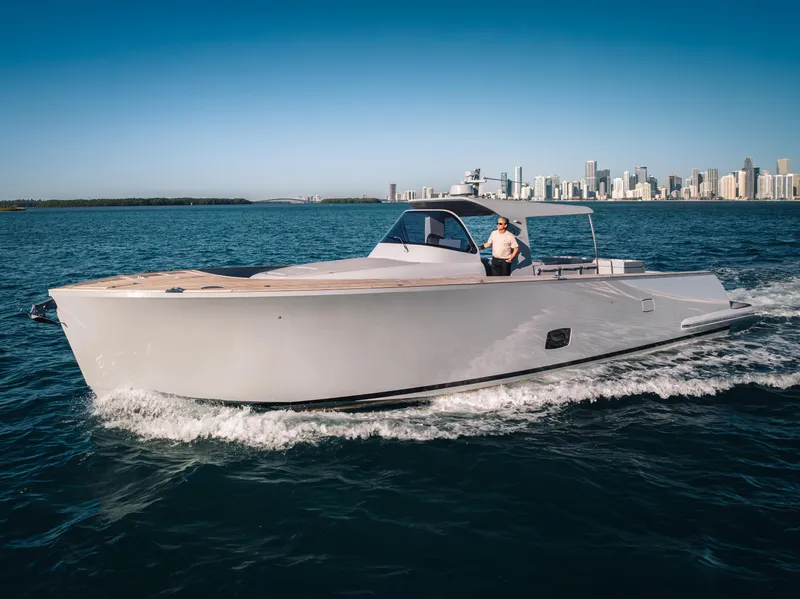Slide: The Image of 2021 Alen 55 yacht cruising on open water with city skyline in background. - 7
