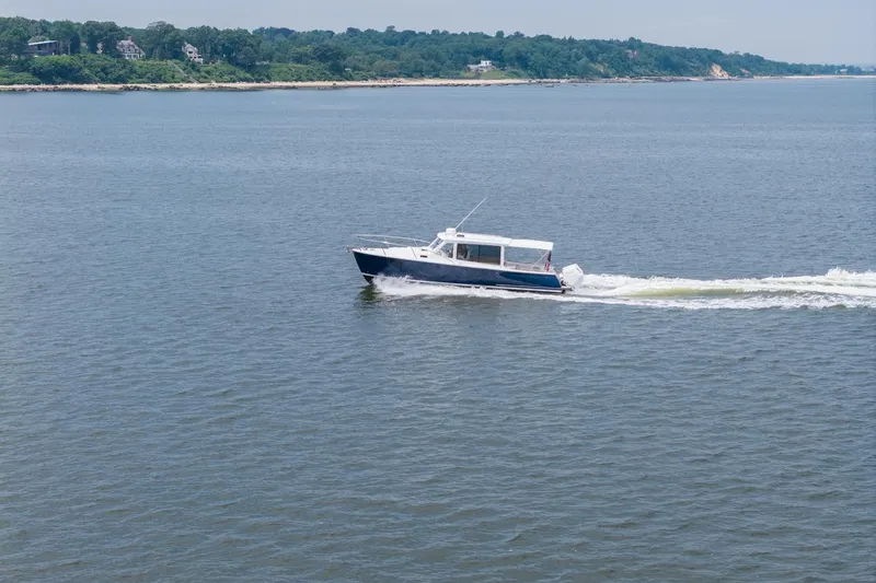Slide: The Image of 2025 MJM 35 boat cruising on a calm lake with scenic shoreline. - 11