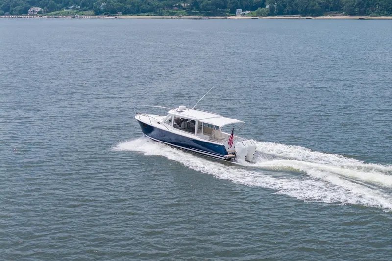 Slide: The Image of 2025 MJM 35 boat cruising on open water with scenic shoreline in background. - 12