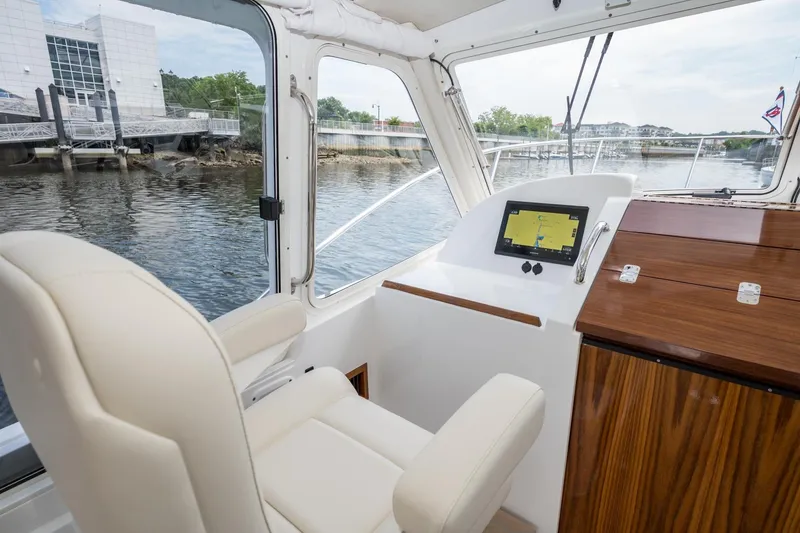 Slide: The Image of Interior of 2025 MJM 35 boat with helm, navigation screen, and waterfront view. - 26