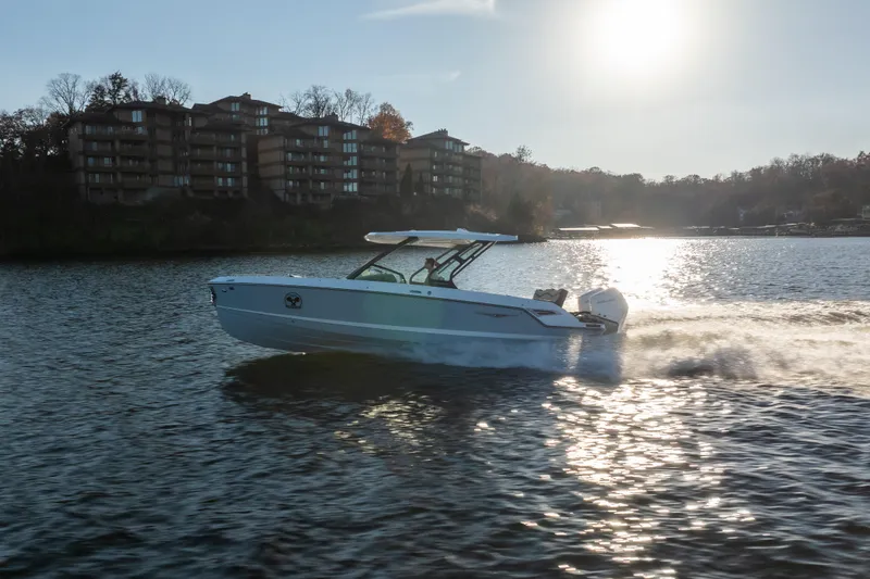 Slide: The Image of 2026 Monterey Elite 30 OB boat cruising on a sunlit lake near waterfront buildings. - 15