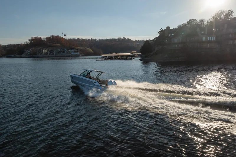 Slide: The Image of 2026 Monterey Elite 30 OB boat cruising on a scenic lake at sunset. - 16