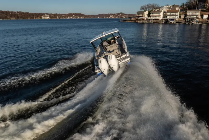 Slide: The Image of 2026 Monterey Elite 30 OB boat cruising on a scenic lake near waterfront homes. - 17