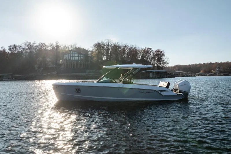 Slide: The Image of 2026 Monterey Elite 30 OB boat on a sunny lake, surrounded by trees and houses. - 4