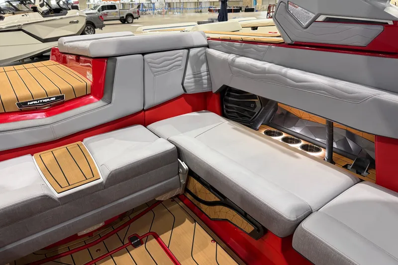 Slide: The Image of 2026 Nautique Super Air Nautique G23 interior with red and gray seating, cup holders, and teak flooring. - 11