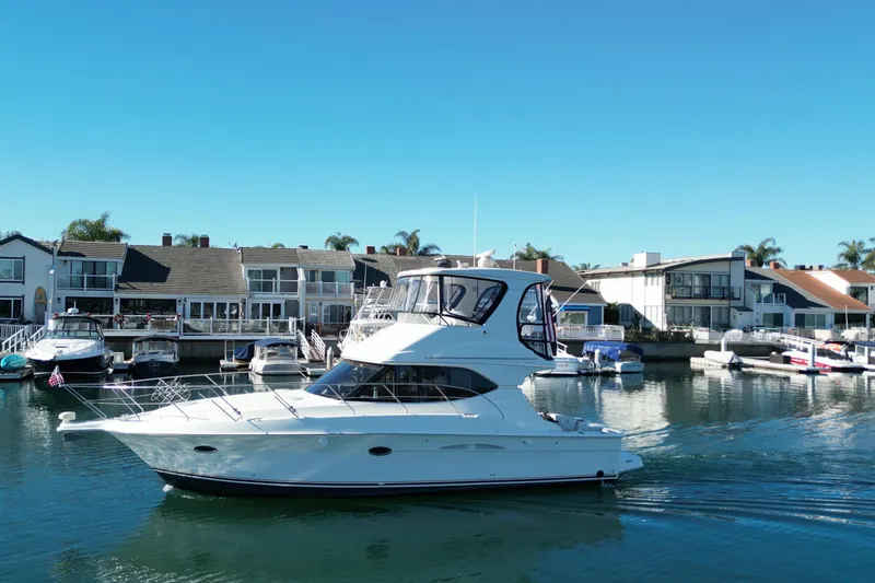 The Image of 2003 Silverton 38 Convertible yacht cruising in a marina with waterfront homes. - 0