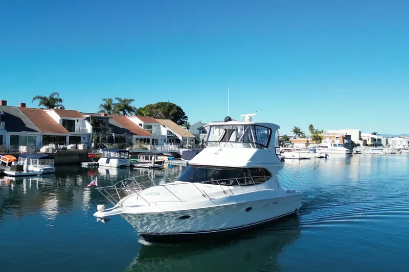 Slide: The Image of 2003 Silverton 38 Convertible yacht cruising in a scenic waterfront neighborhood. - 1