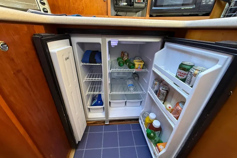 Slide: The Image of 2003 Silverton 38 Convertible yacht kitchen with open fridge stocked with drinks and food. - 17