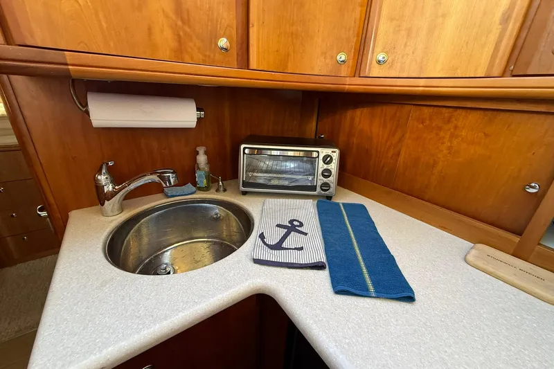 Slide: The Image of 2003 Silverton 38 Convertible yacht kitchen with sink, toaster oven, and nautical-themed decor. - 19