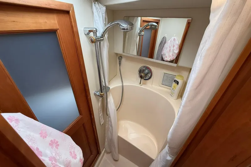Slide: The Image of 2003 Silverton 38 Convertible yacht bathroom with shower, wooden door, and mirror. - 25