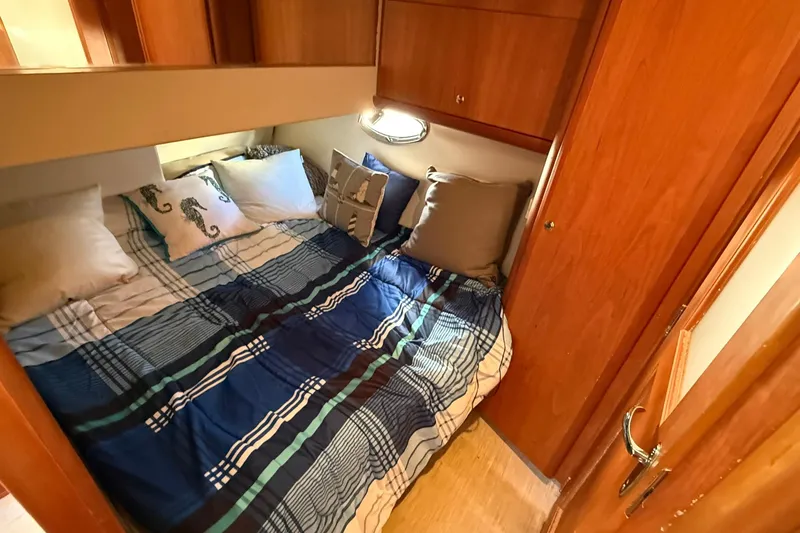 Slide: The Image of 2003 Silverton 38 Convertible cabin with cozy bed and nautical-themed decor. - 27