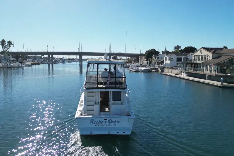 Slide: The Image of 2003 Silverton 38 Convertible boat cruising in a sunny marina with bridge and waterfront homes. - 3