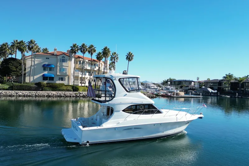 Slide: The Image of 2003 Silverton 38 Convertible yacht cruising near waterfront homes and palm trees. - 4