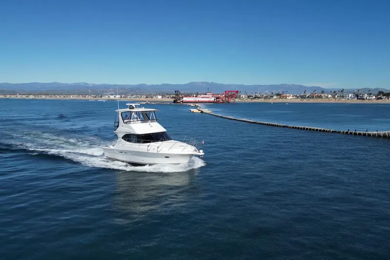 Slide: The Image of 2003 Silverton 38 Convertible yacht cruising near a coastal cityscape. - 7