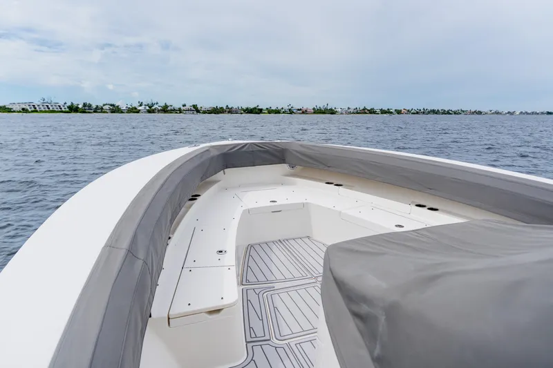 Slide: The Image of 2018 Regulator 41 boat interior with cushioned seating, on calm water, under a cloudy sky. - 125