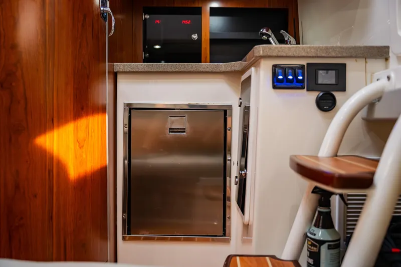 Slide: The Image of 2018 Regulator 41 boat interior with stainless steel fridge, wooden cabinetry, and control panel. - 85