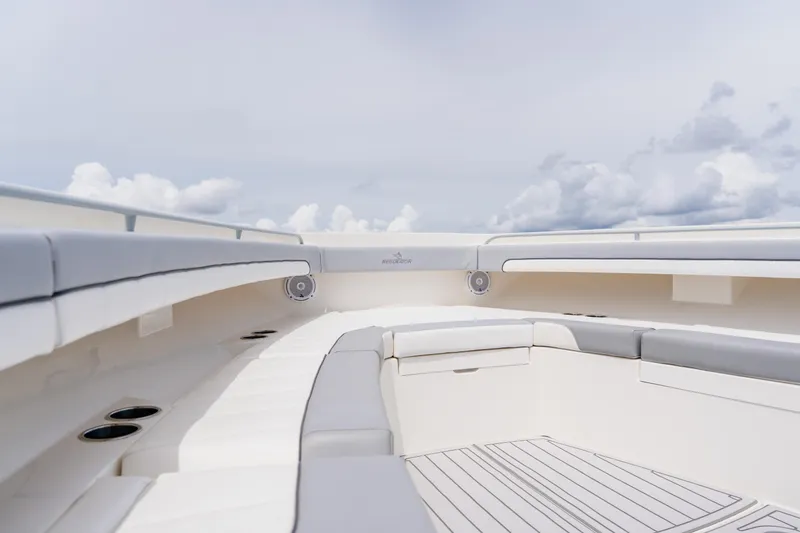 Slide: The Image of 2018 Regulator 41 boat interior with cushioned seating and cup holders under a cloudy sky. - 97