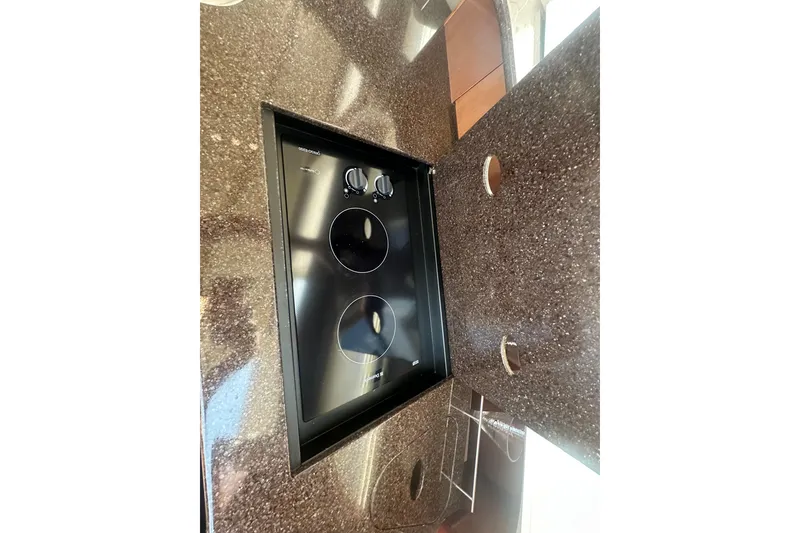 Slide: The Image of 2010 Meridian 391 Sedan kitchen with sleek black cooktop on speckled countertop. - 15